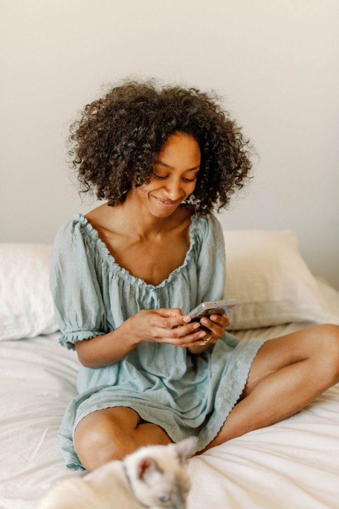 Sanetra Nere Logno smiling at phone in bed_best story podcasts
