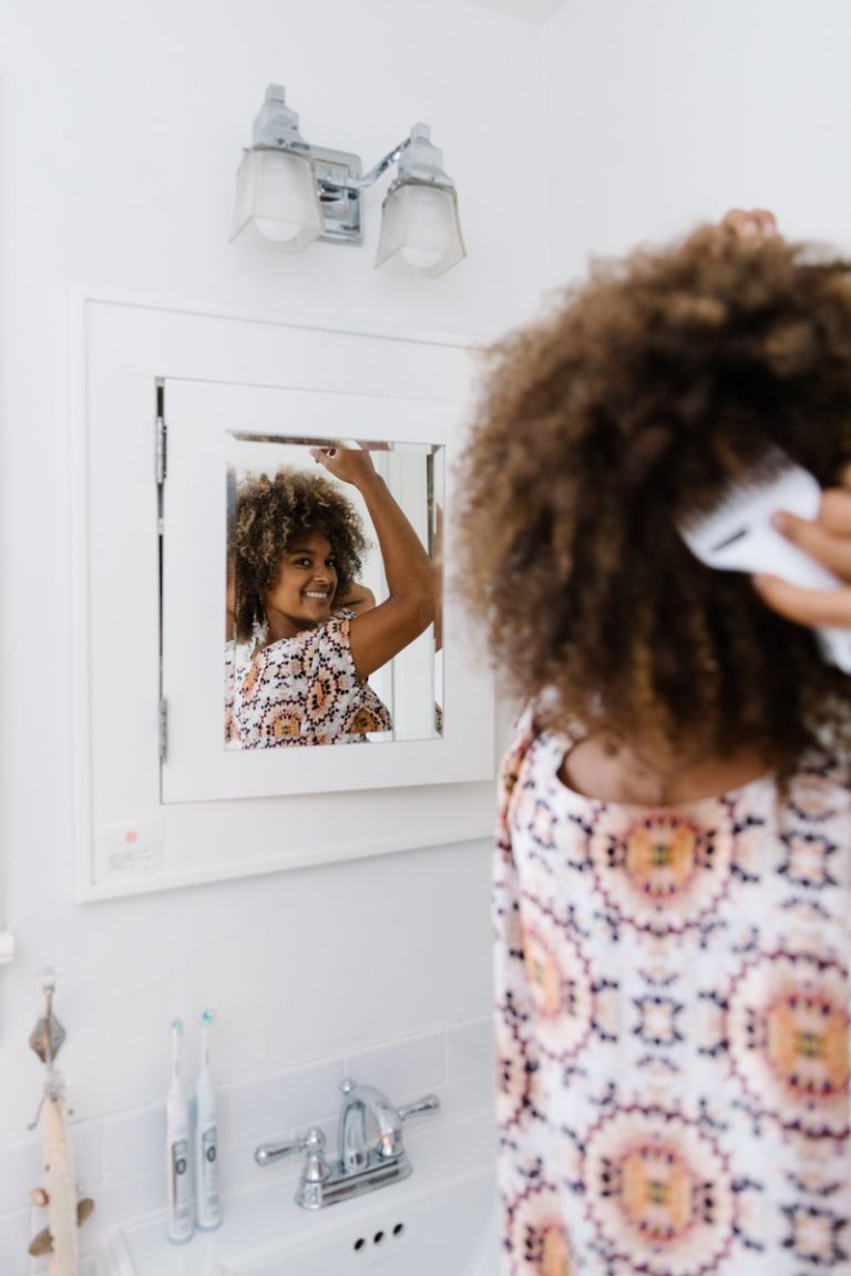 Riley Reed styling hair in mirror