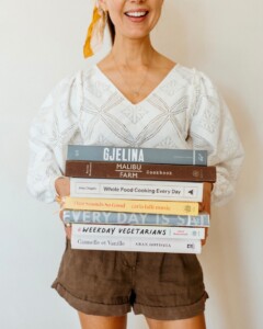 Woman holding stack of beautiful cookbooks.