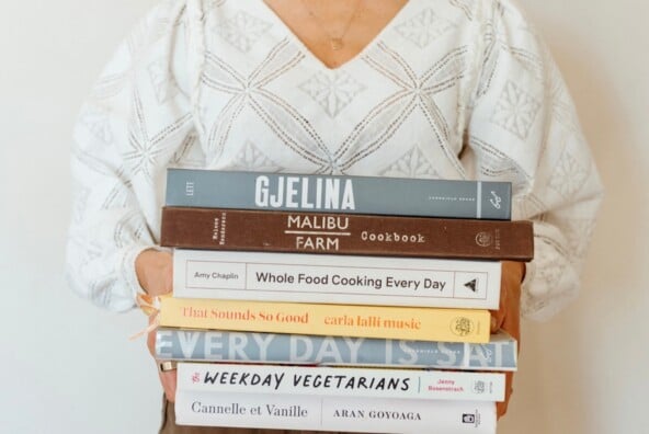 Woman holding stack of beautiful cookbooks.