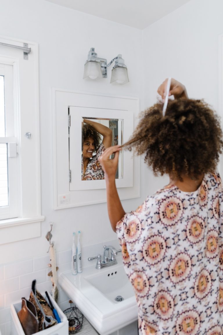Riley Reed styling hair in bathroom mirror