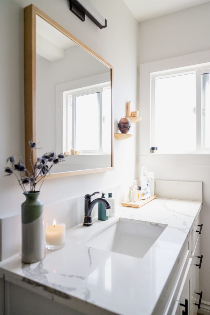 White bathroom vanity with wood-framed mirror
