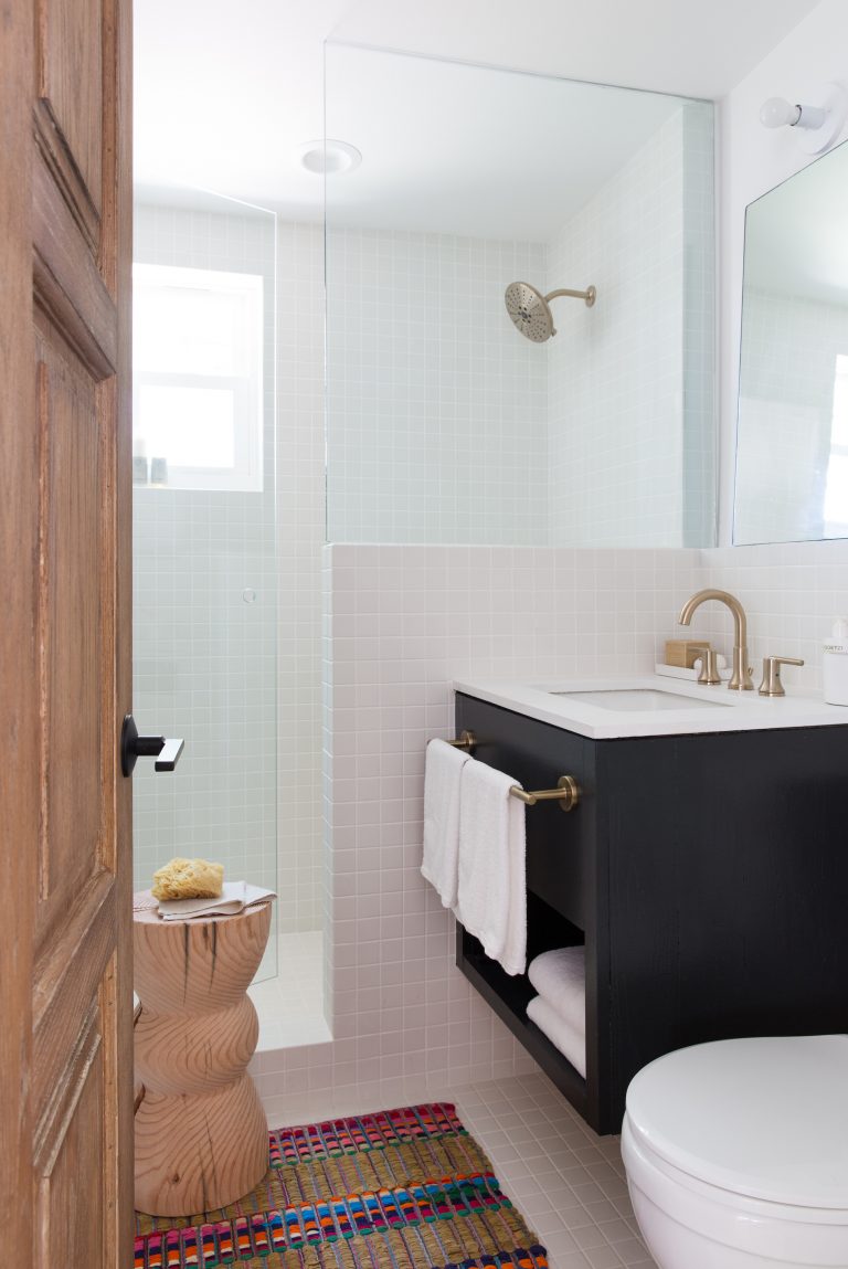 Baño sencillo con tocador negro y azulejos blancos.