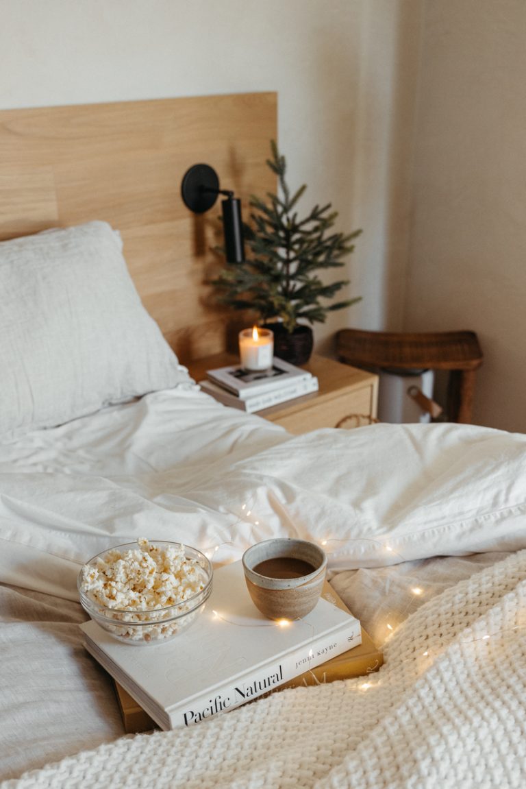 A book of popcorn on the bed Cozy twinkling lights Best classic holiday movies