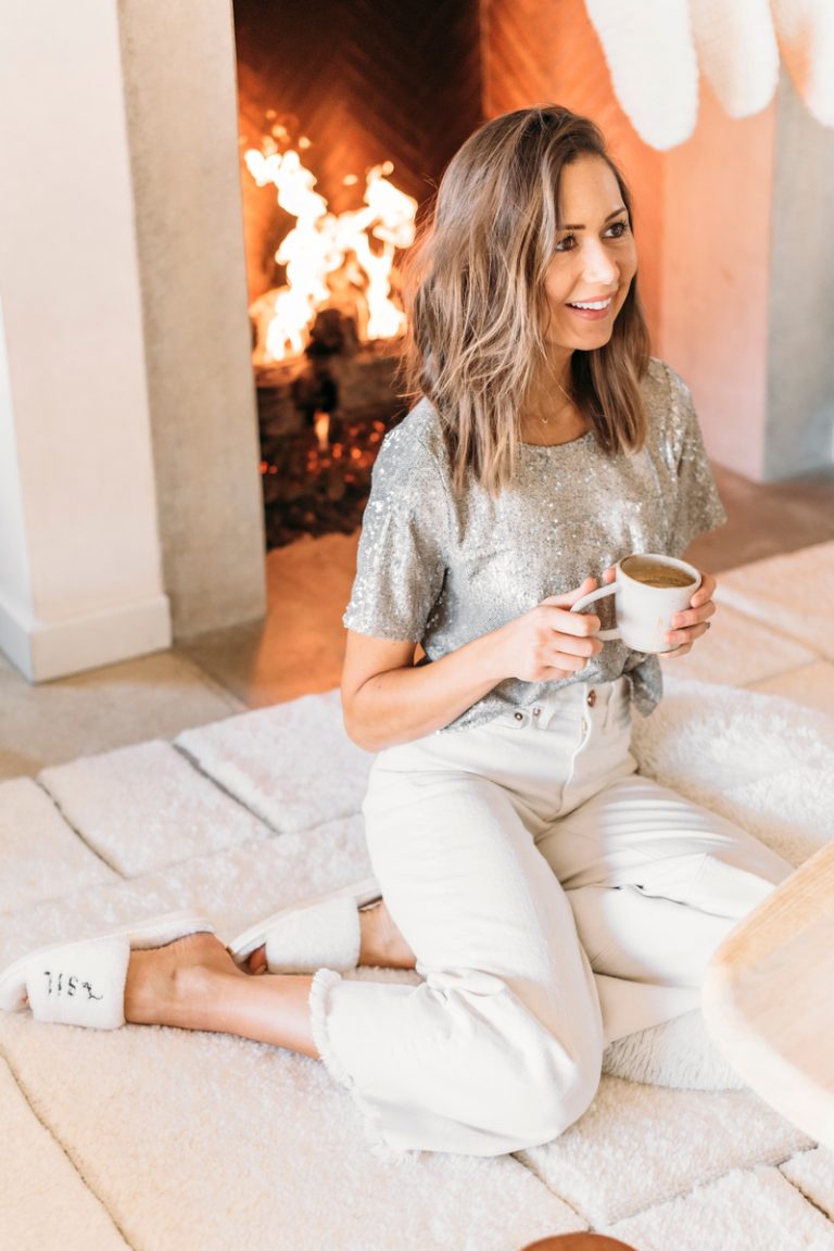 woman drinking tea sitting by fireplace best body butters