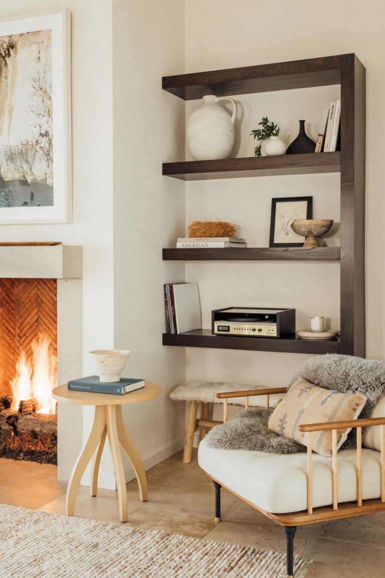 neutral living room with arm chair side table and fireplace