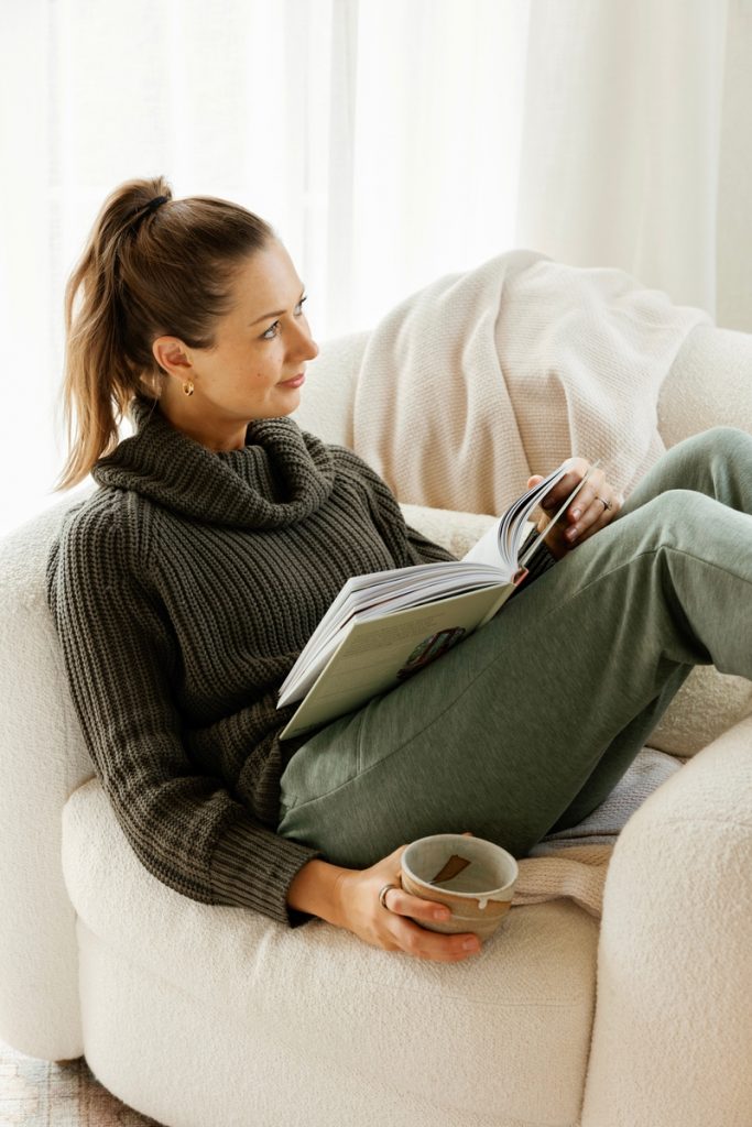 woman wearing loungewear reading in cozy chair winter well being