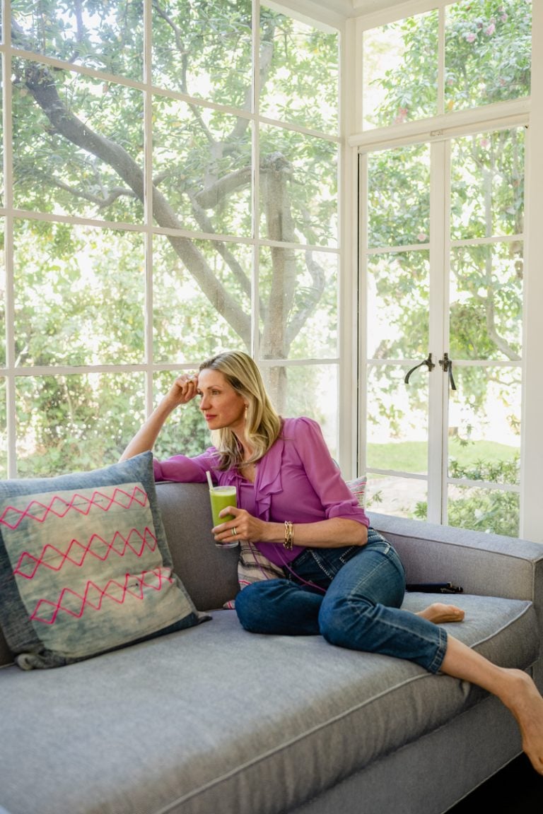 woman sitting on couch drinking green smoothie what's going to save my life in 2023