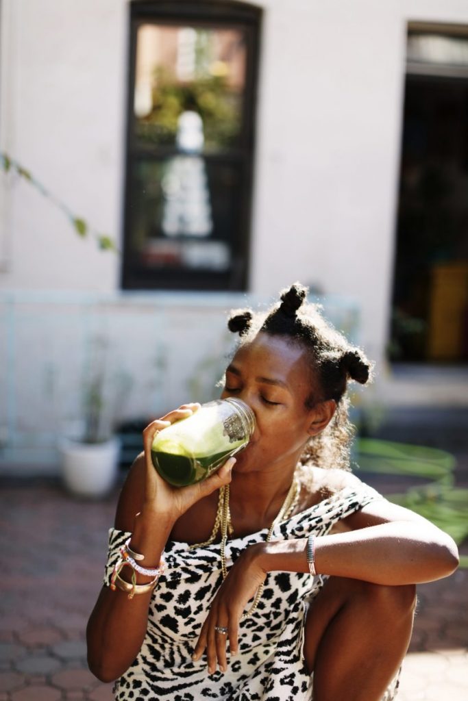 woman drinking green smoothie how to add more dark leafy greens to your diet