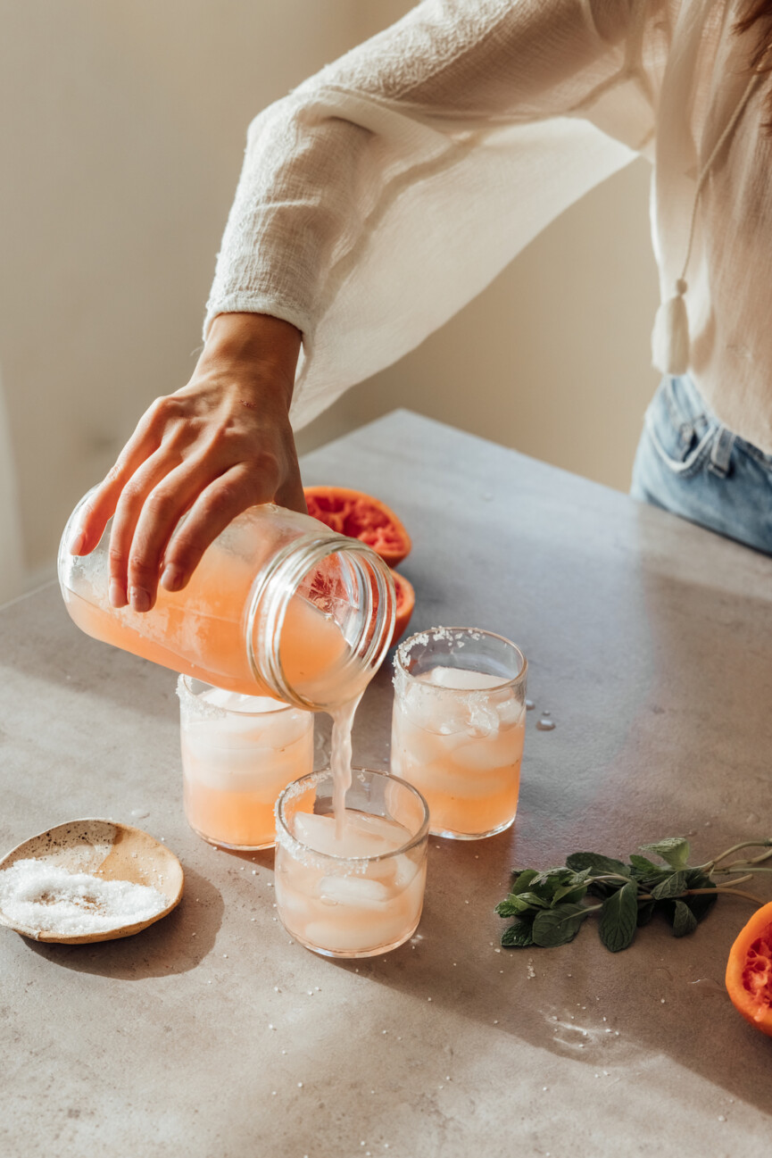 Mujer sirviendo bebidas energéticas saludables en vasos.