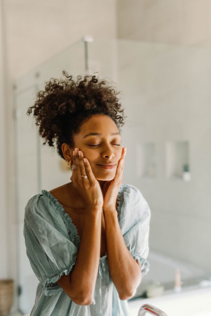 woman applying skincare in mirror