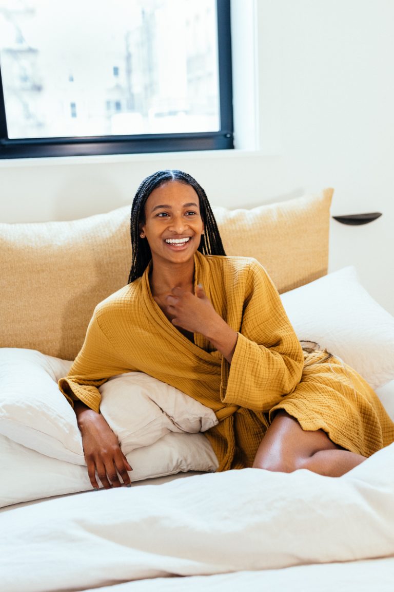 woman smiling wearing yellow robe in bed