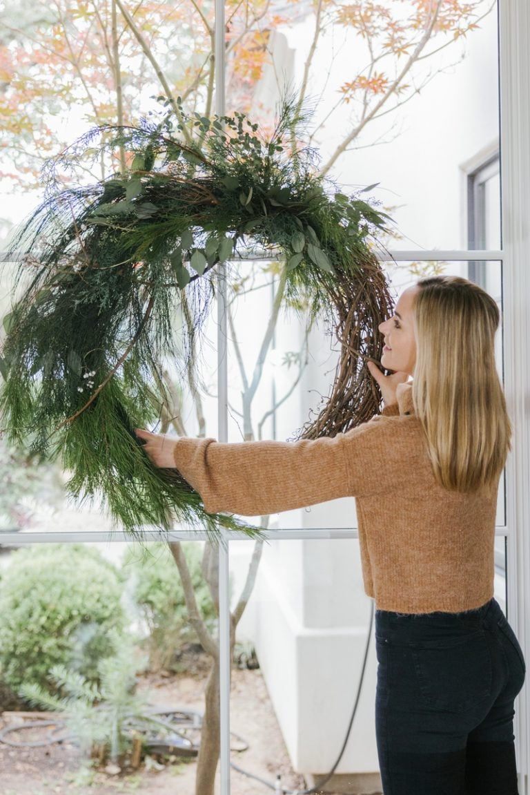 woman hanging wreath holiday traditions