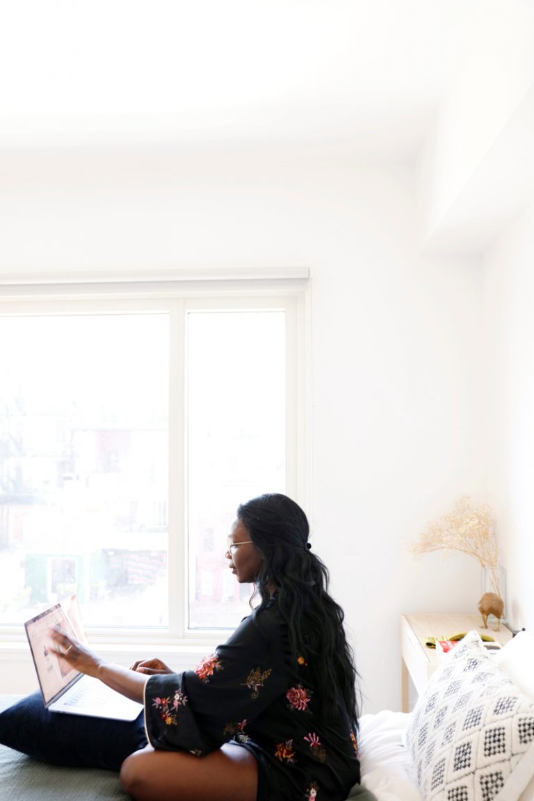 Woman working on laptop in bedroom