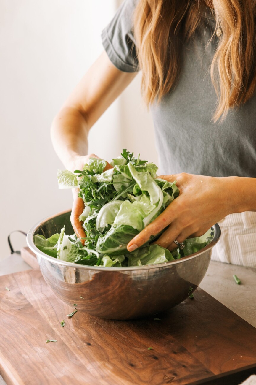 Tossing greenish salad.