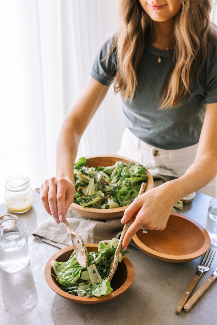 best simple green salad recipe inspired by via carota's insalata verde, camille serving salad in kitchen, cooking