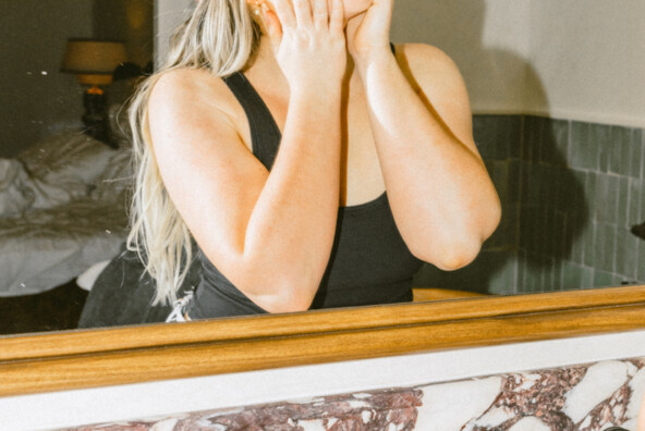 Woman double cleansing in mirror.