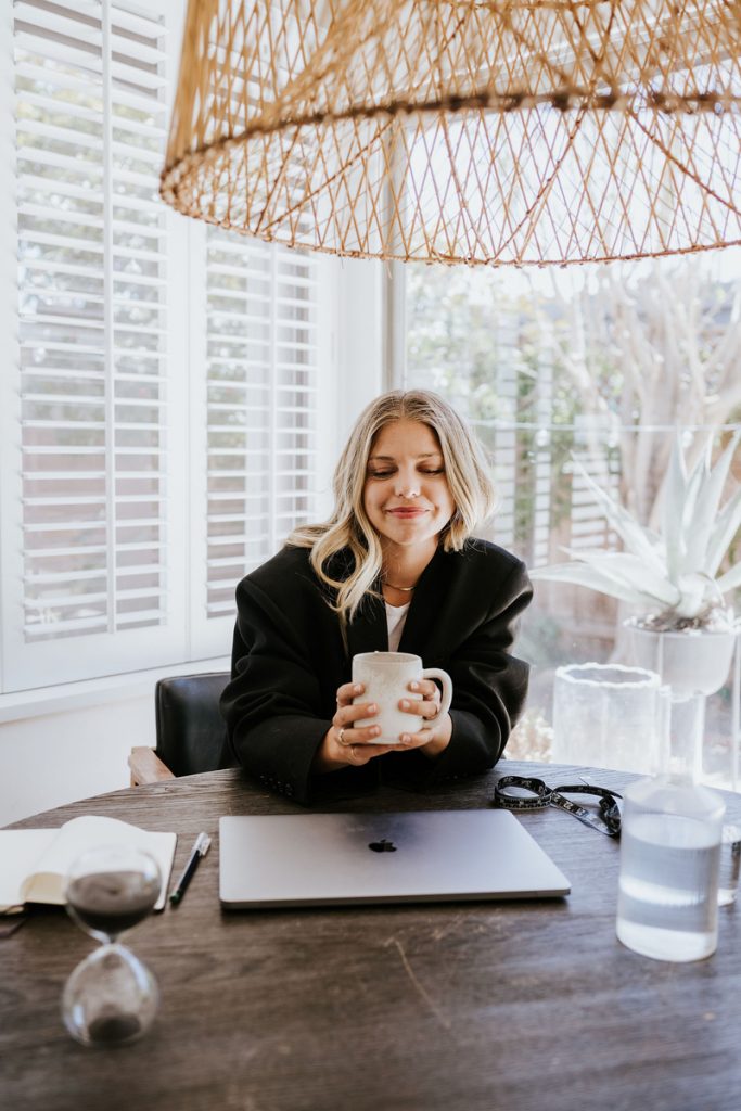 Woman drinking coffee at desk Journal prompts