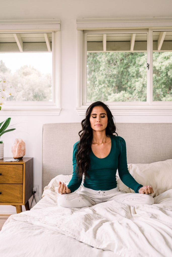 brunette woman meditating in bed