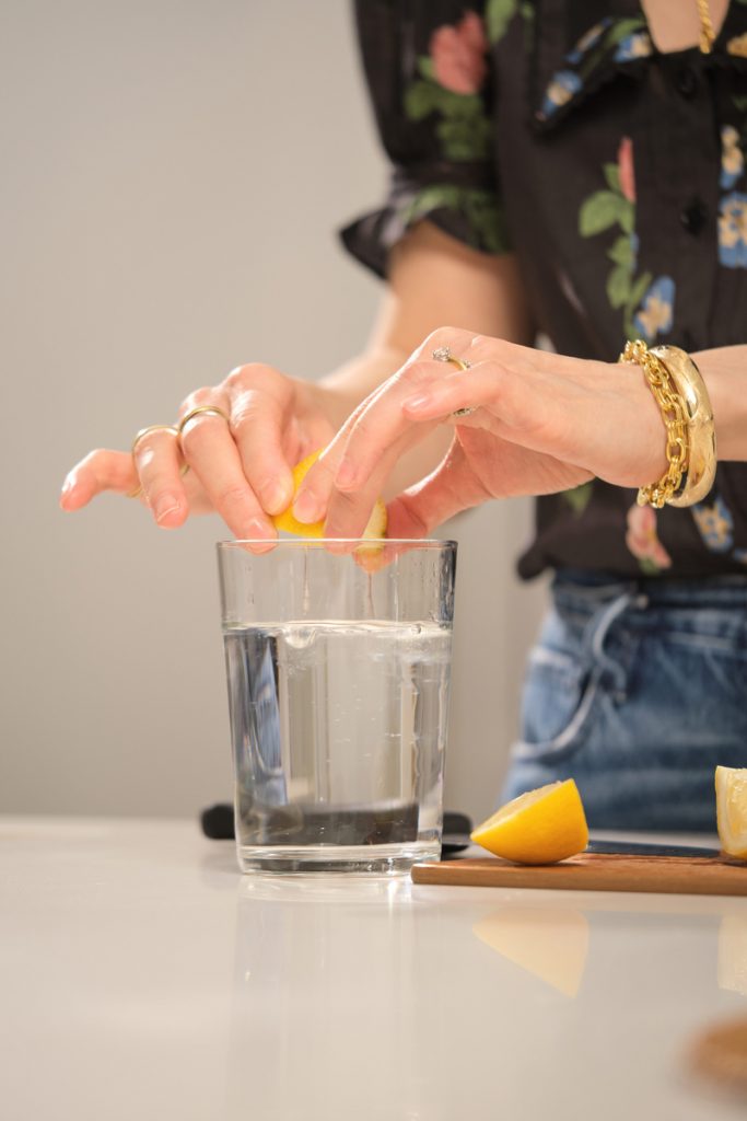 kvinna som pressar citroner i vatten bästa tiden att dricka vatten