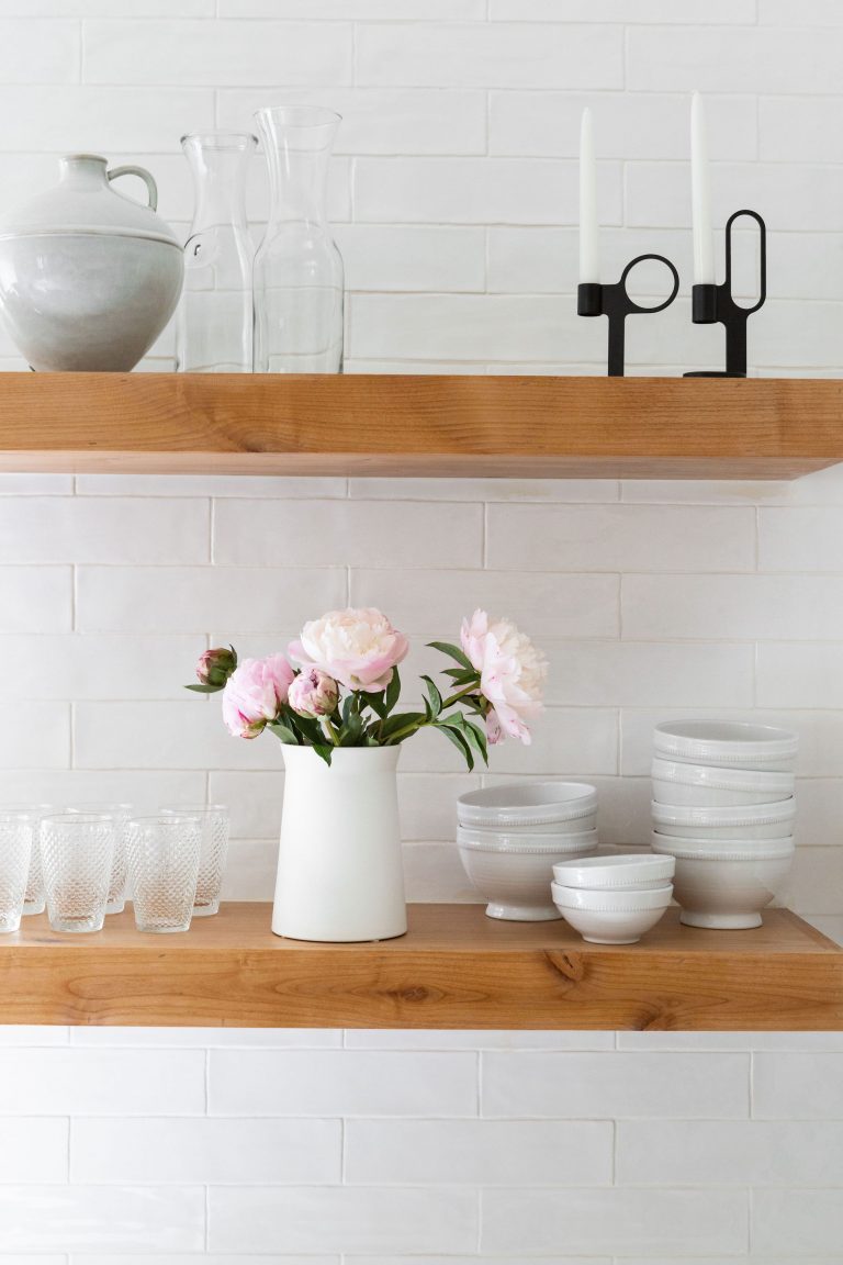white bowls and peonies in white vase on shelf