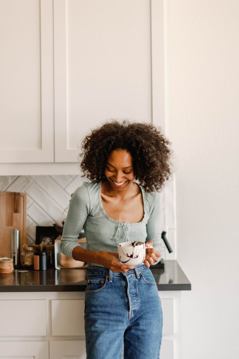 woman drinking coffee in kitchen best hair styling products