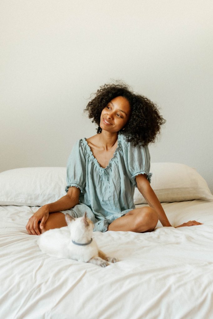 Woman wearing nightgown sitting on bed.