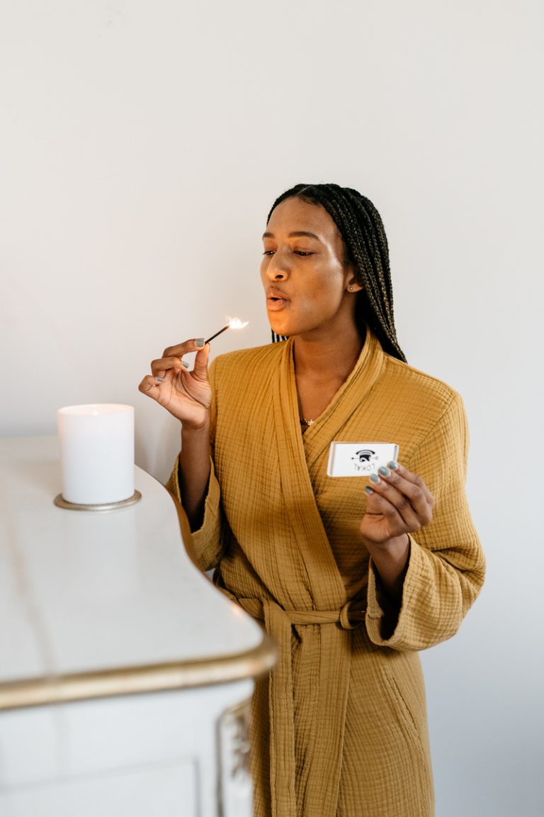 woman blowing out candle wearing yellow robe