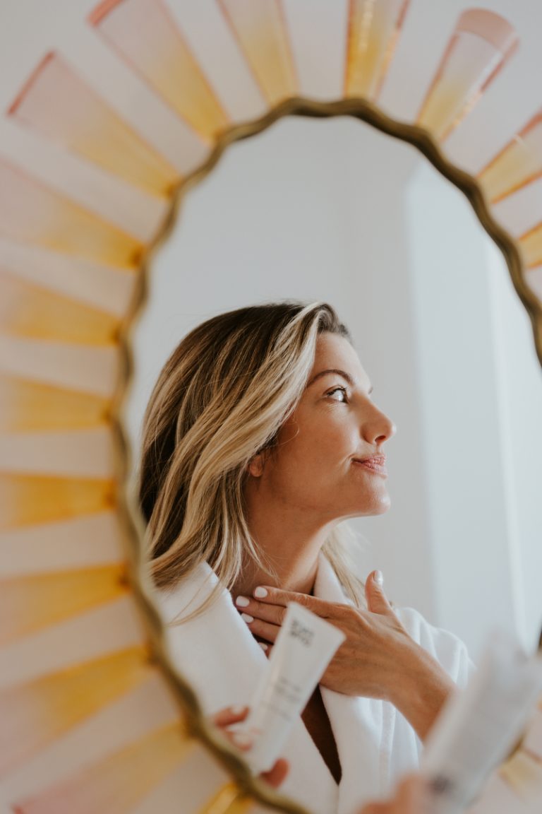 A woman doing skin care in the mirror.