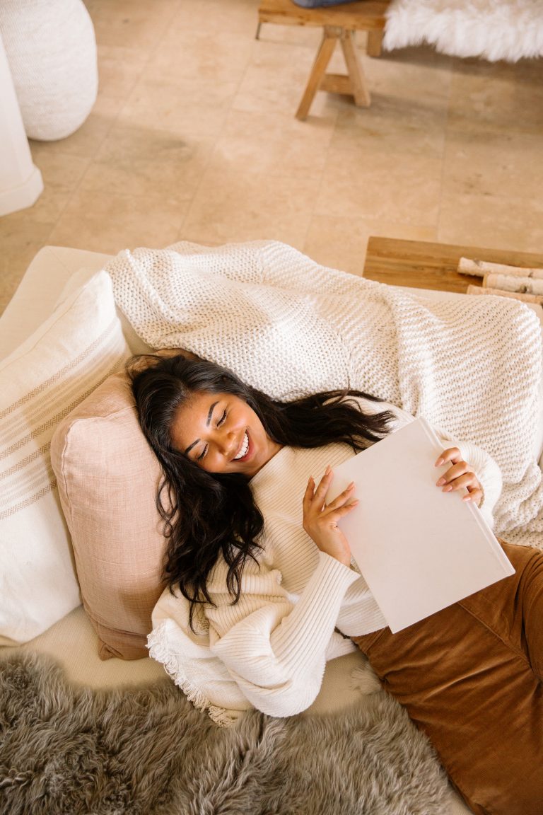 woman laughing on couch holding book sex products