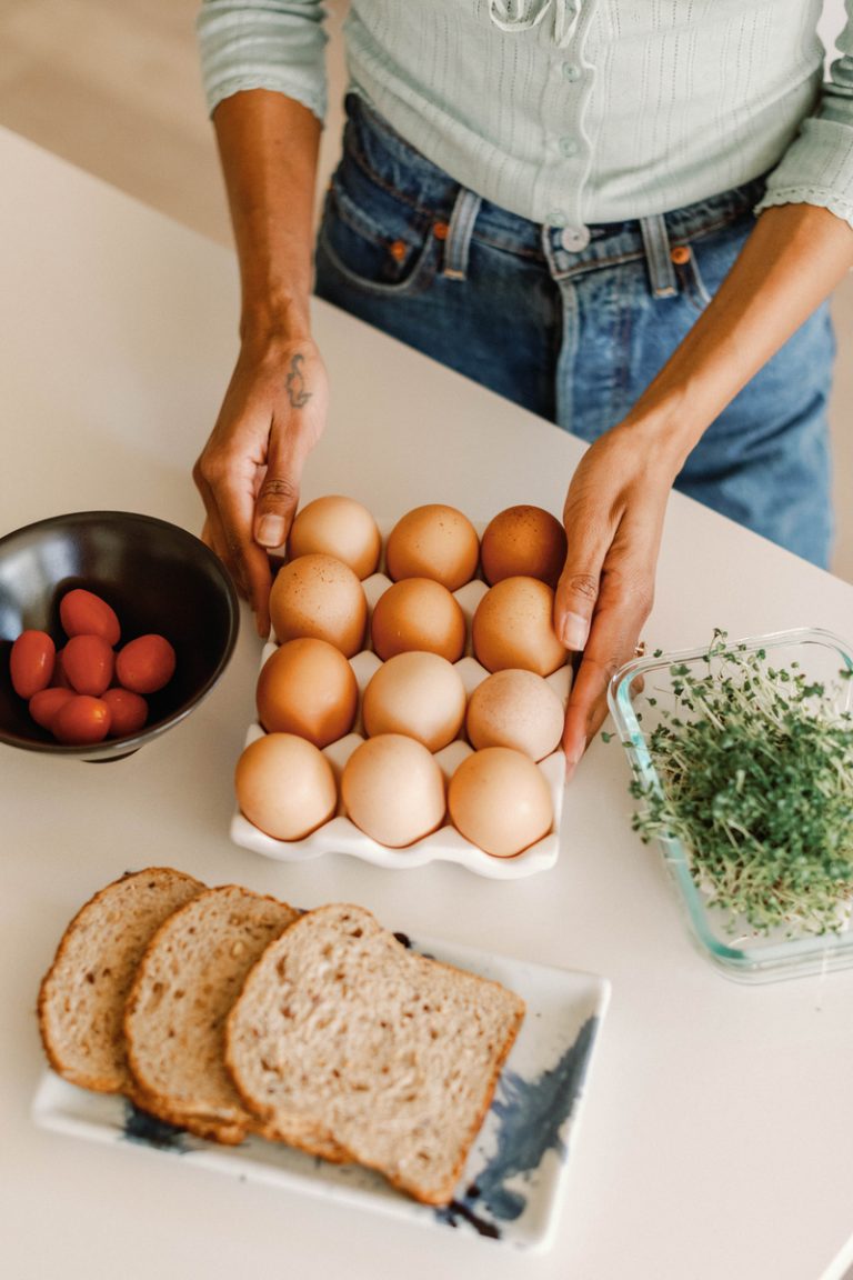 Woman preparing eggs and toast in kitchen.