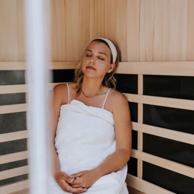 Blonde woman wearing towel in sauna.