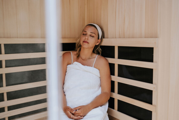 Blonde woman wearing towel in sauna.
