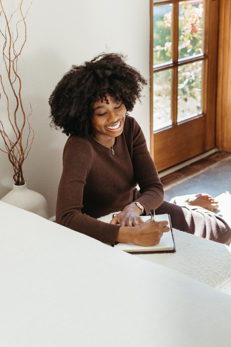 woman smiling and journaling, winter selfcare