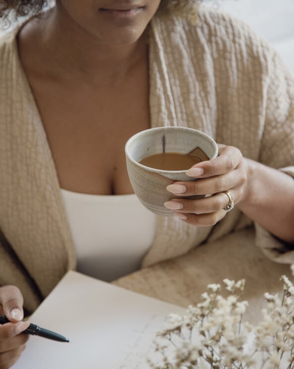 Woman drinking coffee journaling.