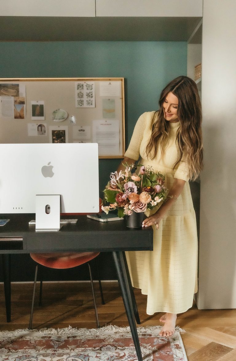 woman arranging flowers in office, office desk decor ideas