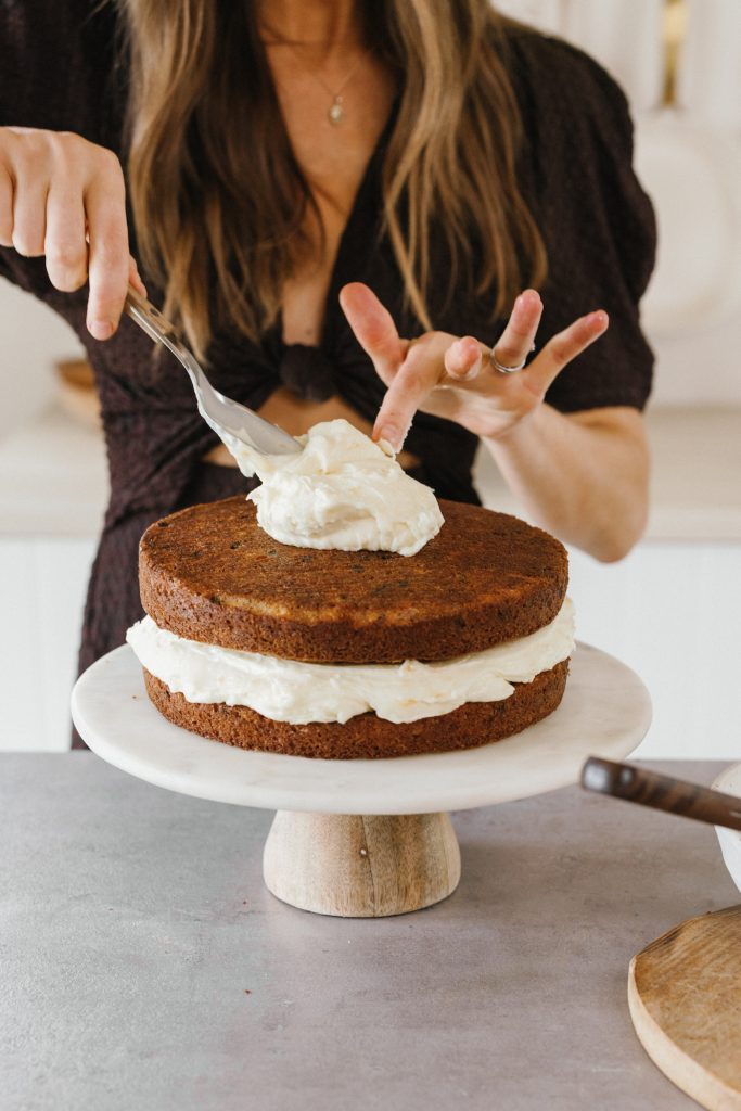 orange carrot cake with cream cheese frosting - camille baking / cooking in kitchen - frosting a cake