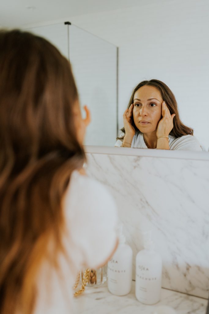 آریل کایه در حال استفاده از مراقبت از پوست در آینه