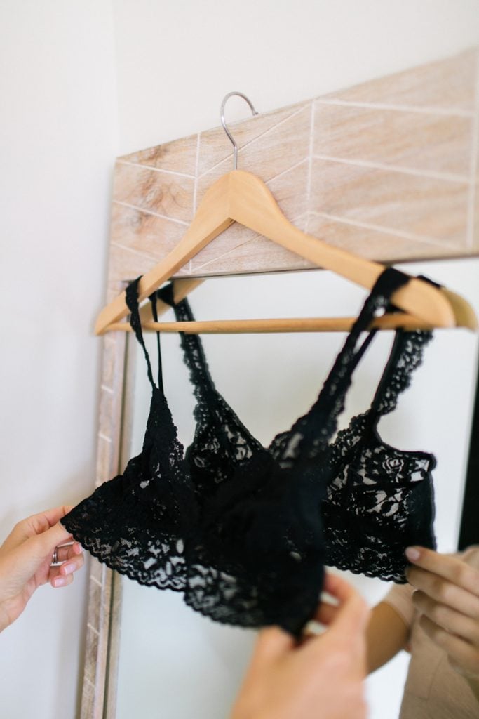 Black lacy bra on hanger hanging from mirror, breast size examples.