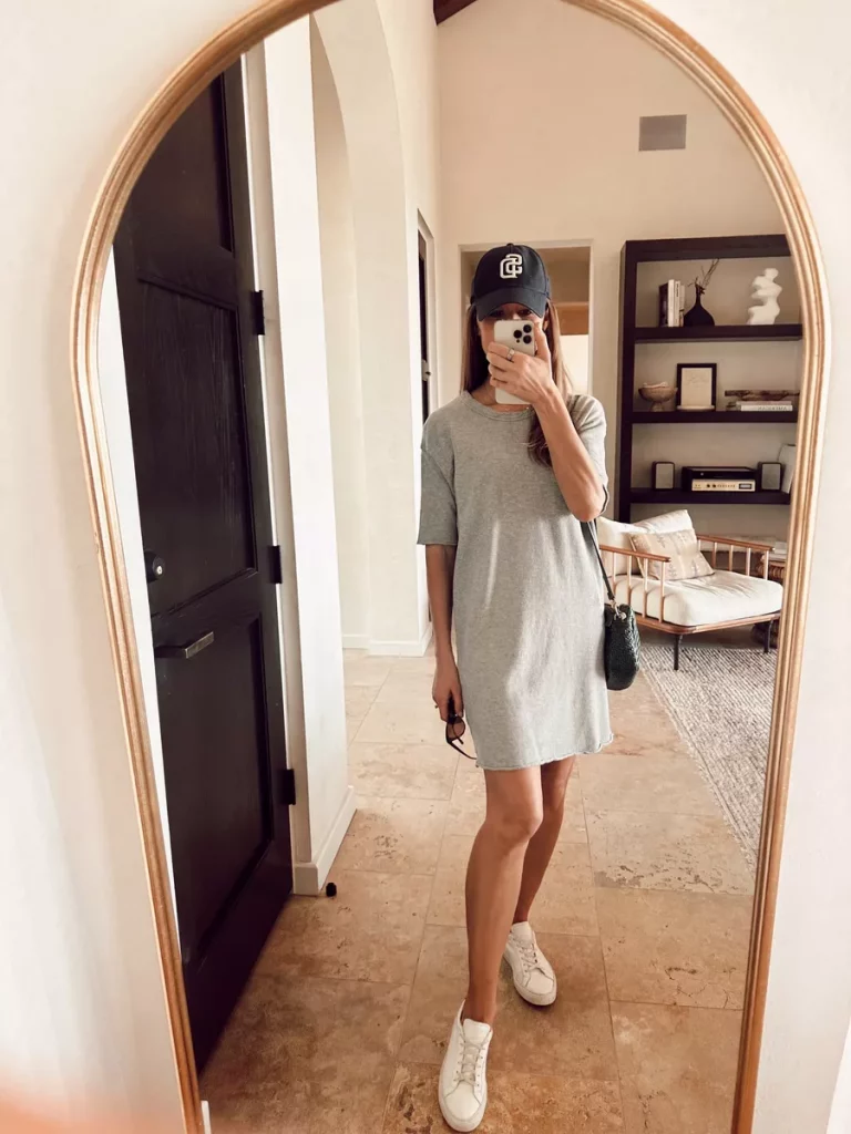 Woman wearing gray midi t-shirt dress with baseball cap and sneakers