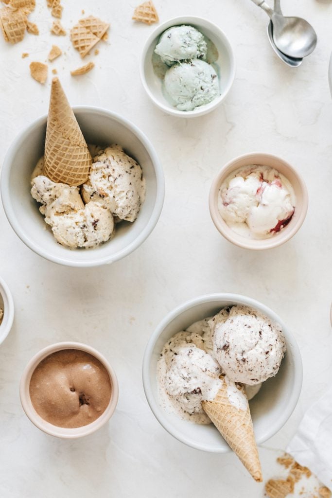 Ice cream scooped into white bowls with cones.