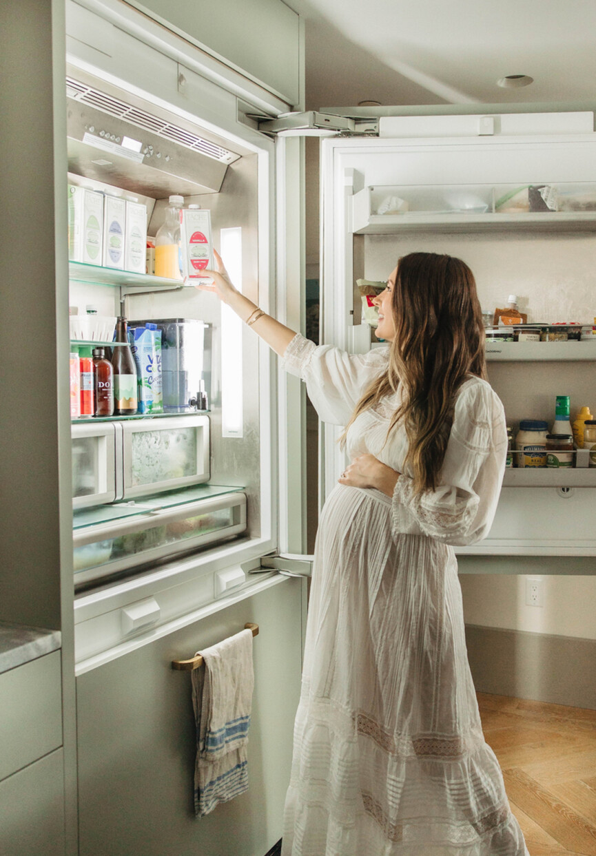 Pregnant woman opening refrigerator.
