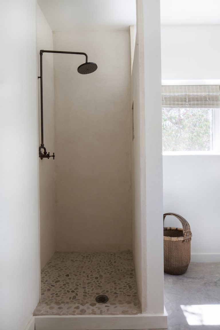 A simple stone shower with white walls.