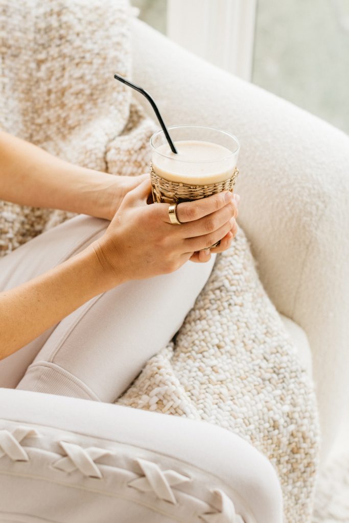 Holding smoothie on white chair with white blanket.