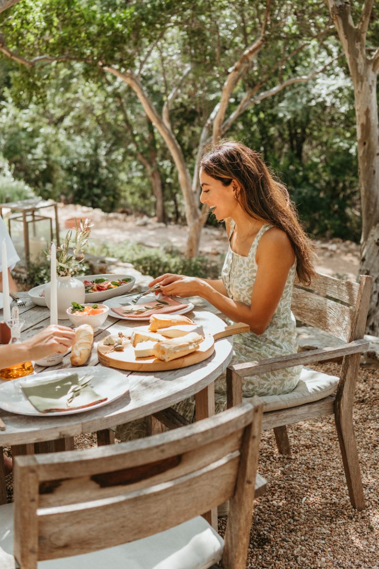 Brunette woman sitting at outdoor brunch table.