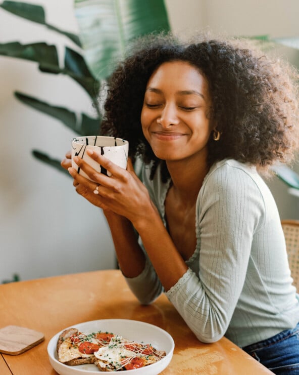 Woman drinking coffee and eating breakfast.