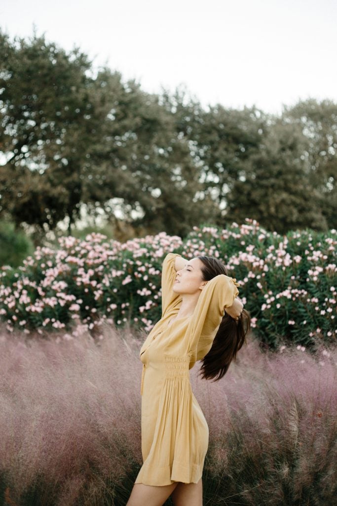 Woman wearing yellow dress standing in field.