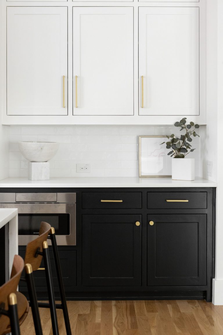 Microwave tucked away in white and black sleek modern kitchen.