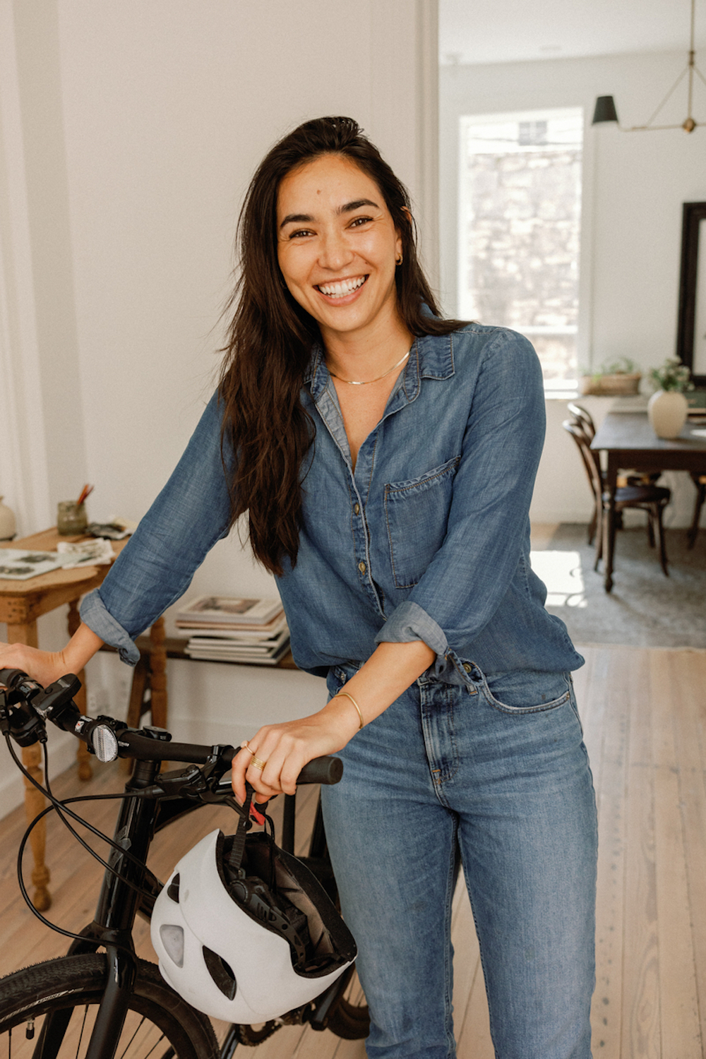 Brunette woman walking bike through house.