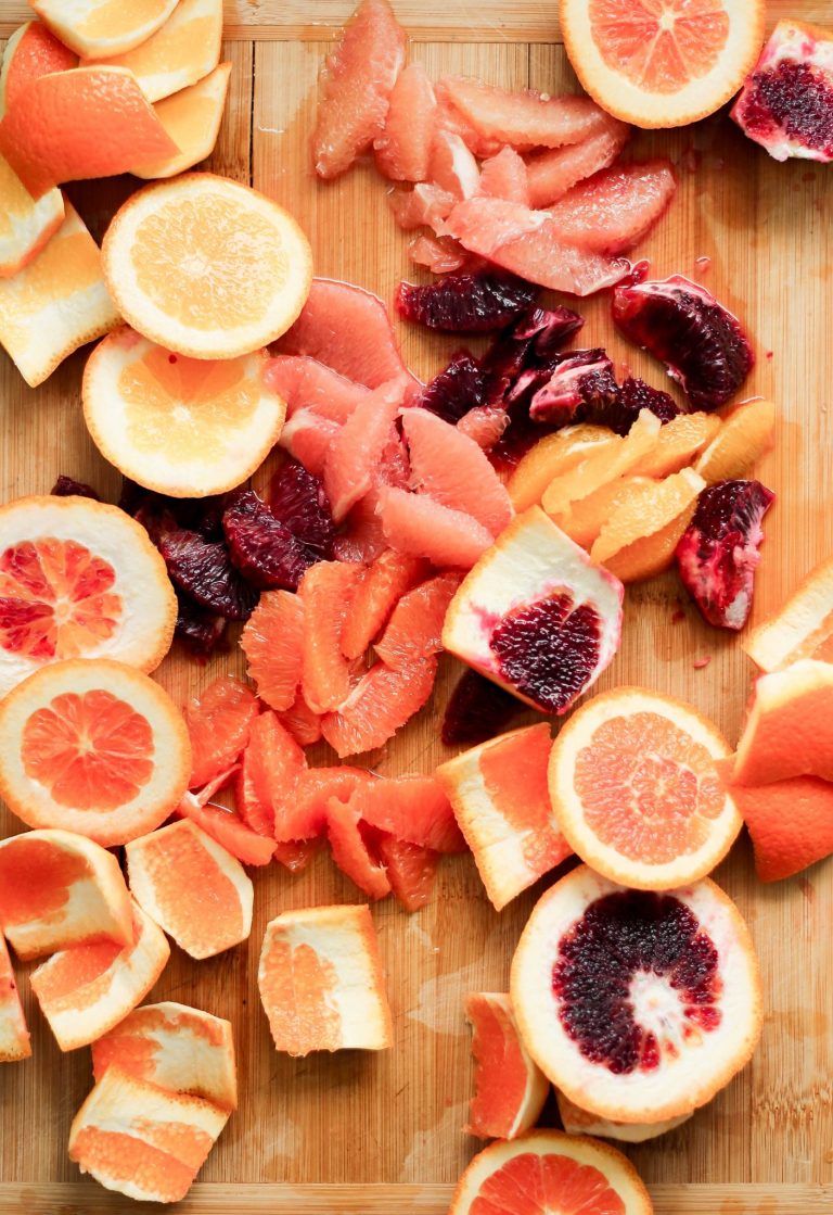 Blood orange, grapefruit, and orange slices on wooden cutting board.